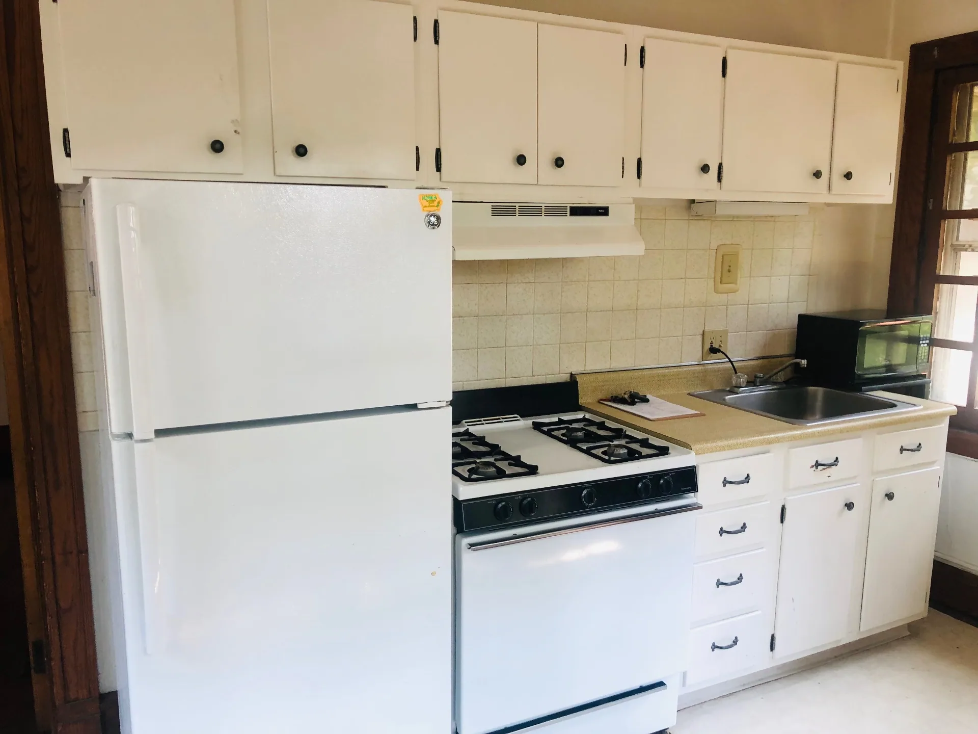 2026 Iuka Ave C kitchen with white cabinets, gas range, refrigerator, and tile backsplash