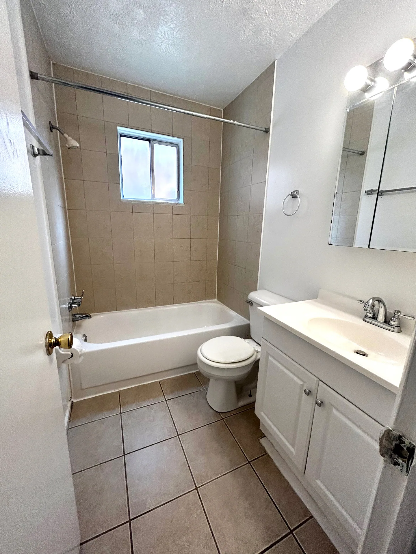 2150 N 4th St. Unit C full bathroom with tiled tub surround, window, and white vanity