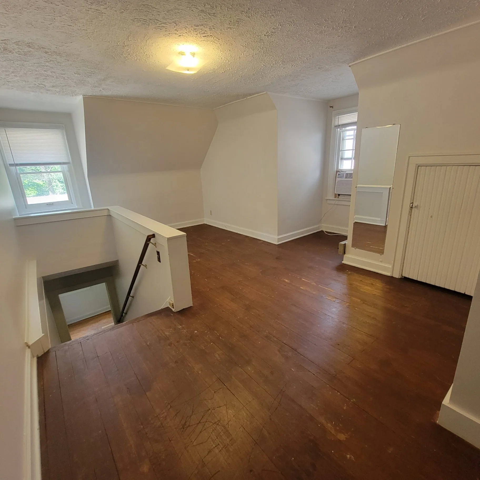 2048 Iuka Ave. C upstairs bedroom with hardwood floors, window A/C, and closet