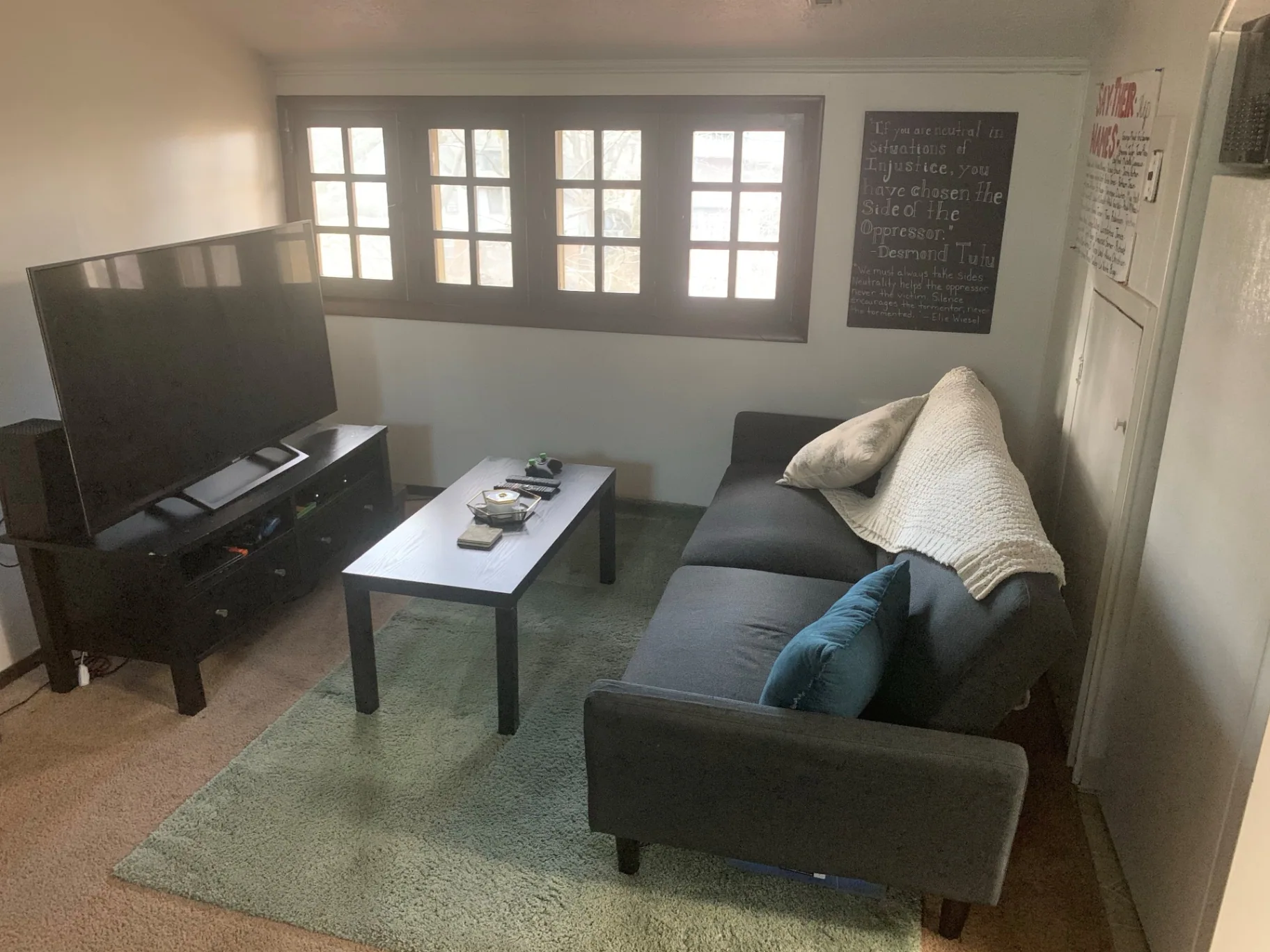 Furnished top-floor living room with grey sofa, TV, and bright transom windows