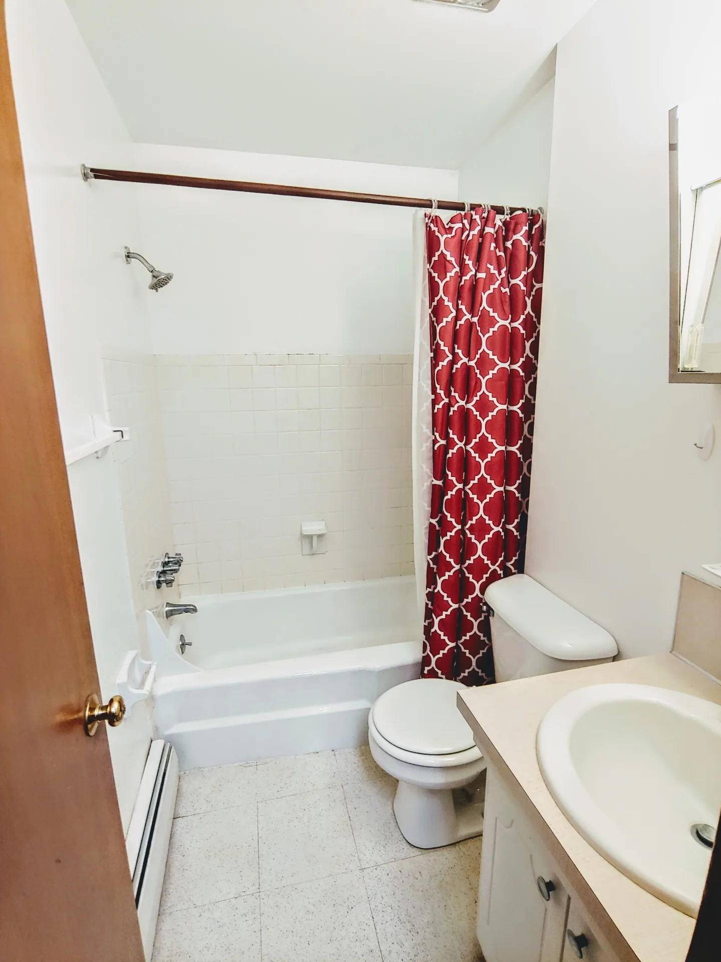 2040 Iuka Ave. 4A bathroom with white tiled tub, red patterned curtain, and vanity