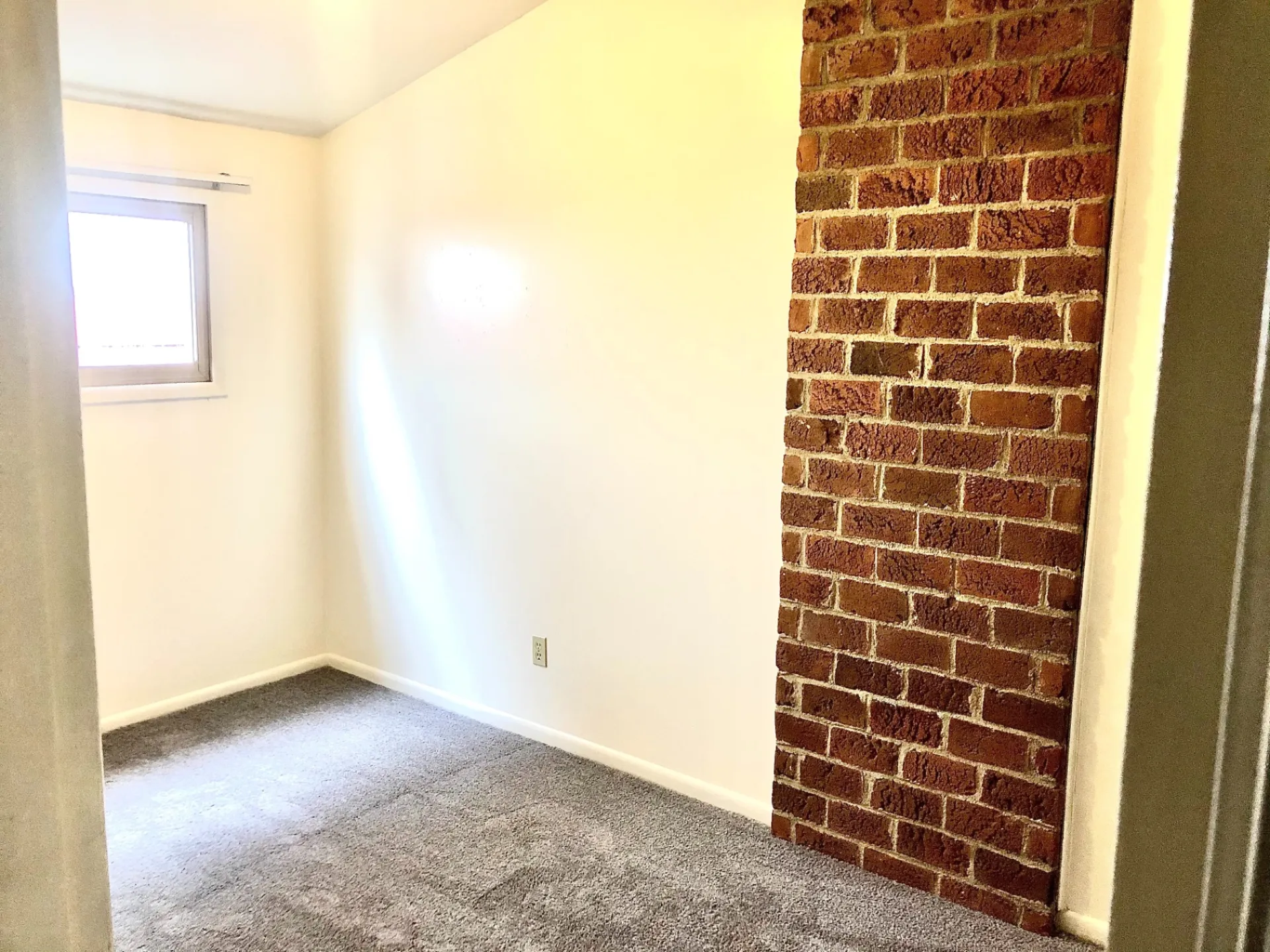 2011 Summit St. Unit F bedroom with exposed red brick accent wall and soft gray carpet