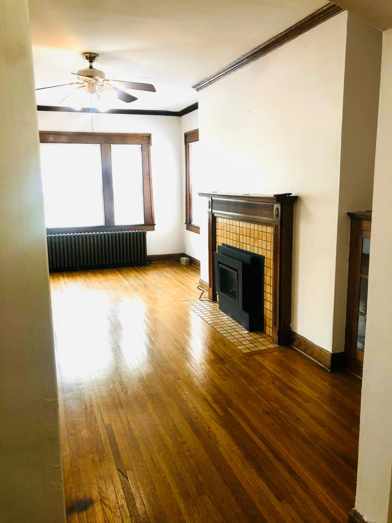 Unit L living room with tiled gas fireplace, hardwood floors, and large sunlit windows