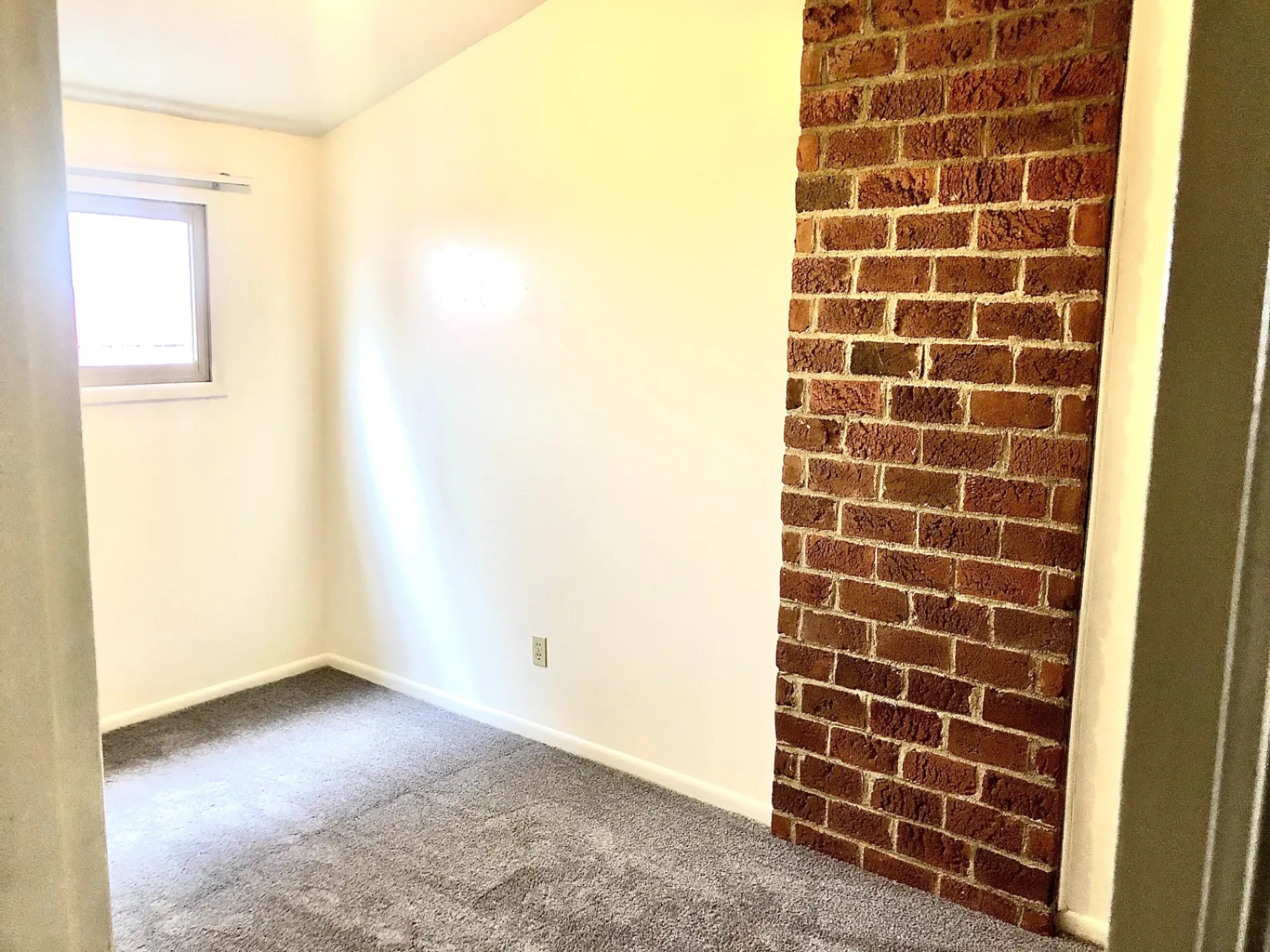 2011 Summit St. Unit B carpeted bedroom with exposed brick accent wall